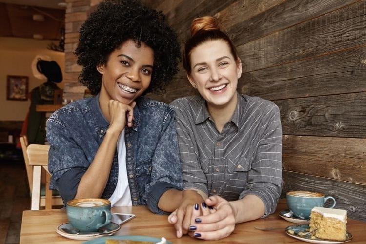 lesbian couple holding hands at a coffee shop